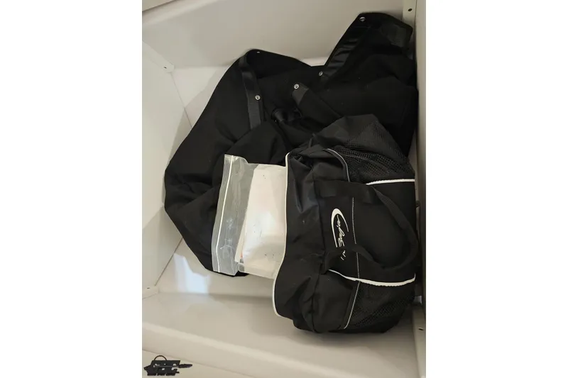 Slide: The Image of Black bags stored in a compartment of a 2018 Baja 24 Outlaw boat. - 89
