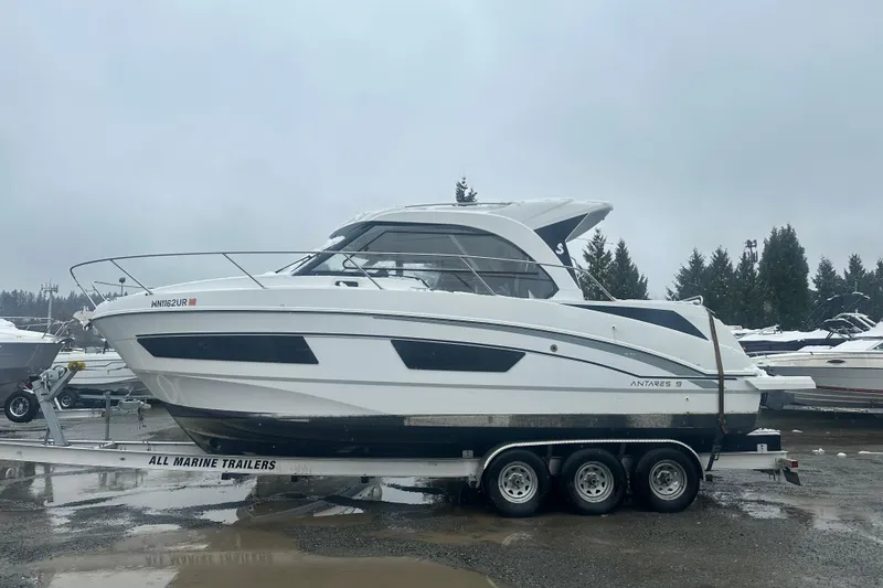Slide: The Image of 2023 Beneteau Antares 9 boat on trailer, parked outdoors on a cloudy day. - 2