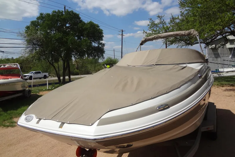 Slide: The Image of 2013 Crownline Eclipse E4 boat covered with a beige tarp, parked outdoors. - 46