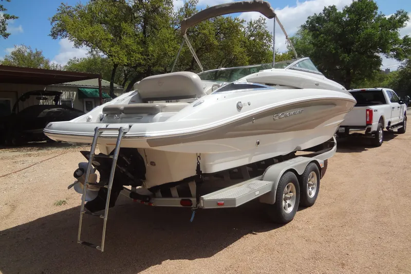Slide: The Image of 2013 Crownline Eclipse E4 boat on trailer, parked outdoors with trees in background. - 5