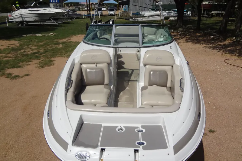 Slide: The Image of 2013 Crownline Eclipse E4 boat with beige seating, parked on sandy ground. - 9