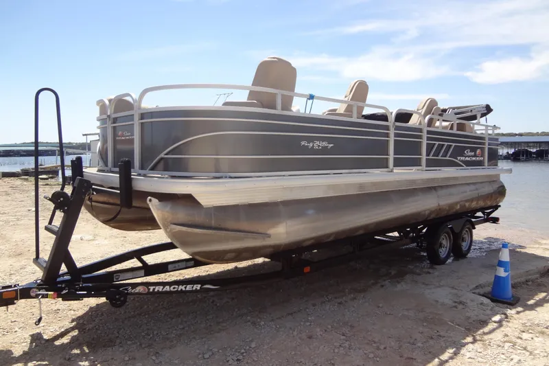 Slide: The Image of 2022 TRACKER MARINE Party Barge 24 DLX pontoon boat on trailer by the water. - 10