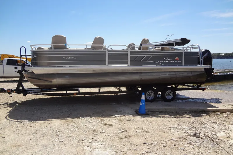 Slide: The Image of 2022 TRACKER MARINE Party Barge 24 DLX pontoon boat on trailer by lakeside. - 11