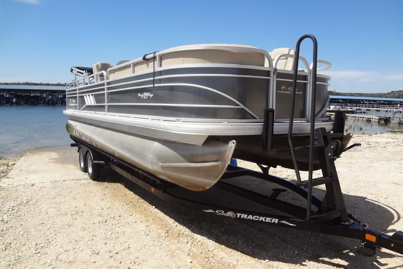 Slide: The Image of 2022 TRACKER MARINE Party Barge 24 DLX pontoon boat on trailer by the water. - 13