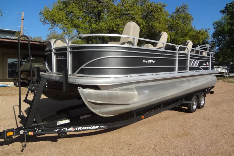 Slide: The Image of 2022 TRACKER MARINE Party Barge 24 DLX pontoon boat on trailer, parked outdoors. - 17