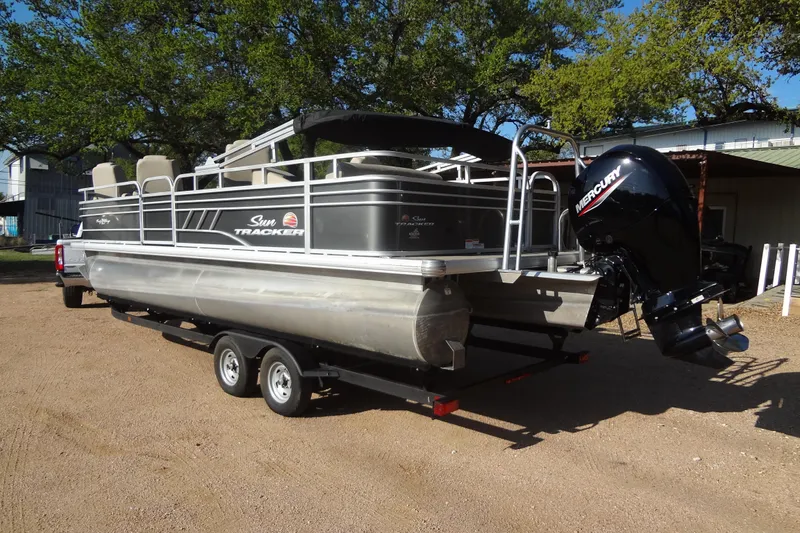 Slide: The Image of 2022 TRACKER MARINE Party Barge 24 DLX pontoon boat on trailer, parked outdoors. - 22