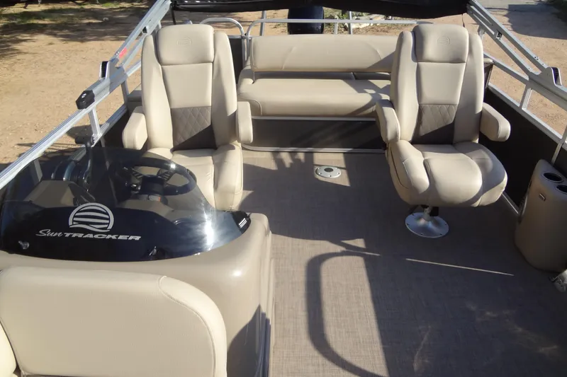 Slide: The Image of 2022 TRACKER MARINE Party Barge 24 DLX interior with beige seating and steering console. - 27