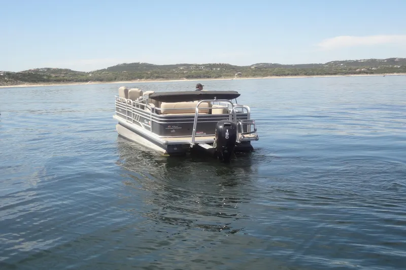 Slide: The Image of 2022 TRACKER MARINE Party Barge 24 DLX pontoon boat on calm lake waters. - 6