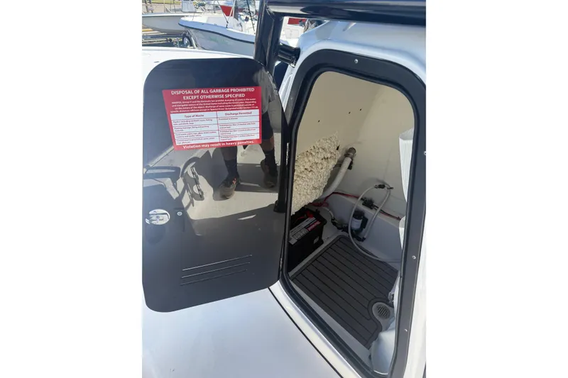 Slide: The Image of 2022 Tidewater 2410 Bay Max boat storage compartment with warning label and equipment. - 33