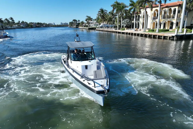 Slide: The Image of 2021 Axopar 28 T-Top boat cruising on a scenic waterway with luxury homes. - 15