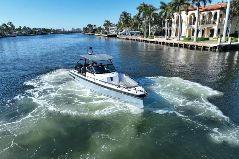 Slide: The Image of 2021 Axopar 28 T-Top boat cruising on a scenic waterway with luxury homes. - 16