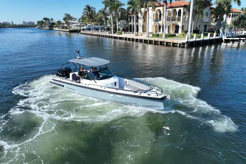 Slide: The Image of 2021 Axopar 28 T-Top boat cruising near luxury waterfront homes. - 17