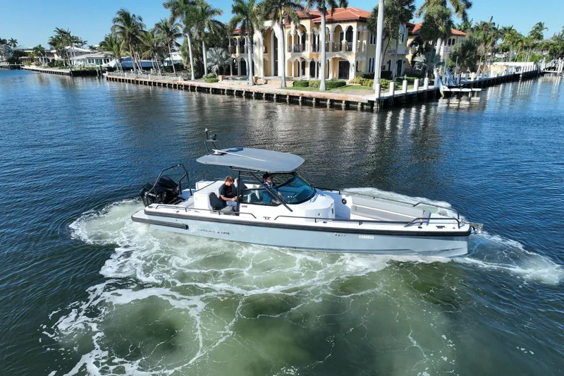 Slide: The Image of 2021 Axopar 28 T-Top cruising near waterfront mansion with palm trees. - 18