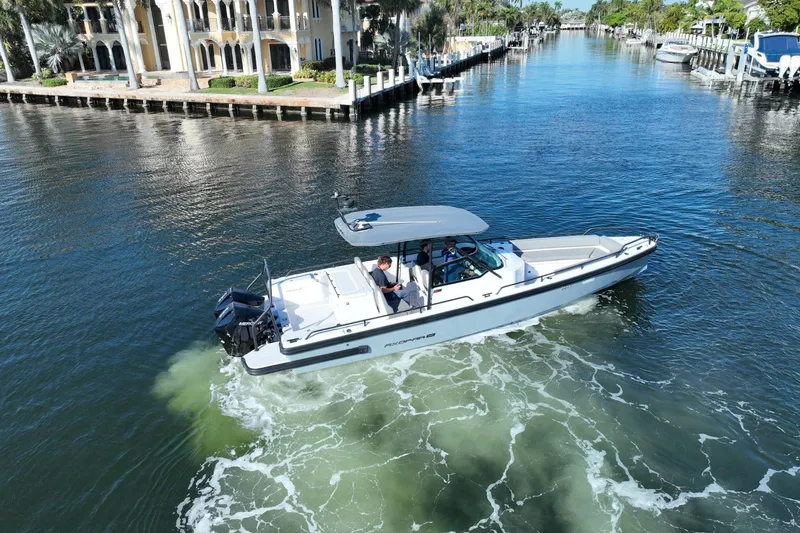 Slide: The Image of 2021 Axopar 28 T-Top cruising in a scenic canal with waterfront homes. - 19