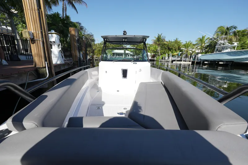 Slide: The Image of 2021 Axopar 28 T-Top boat with spacious seating, docked near tropical palm trees. - 23