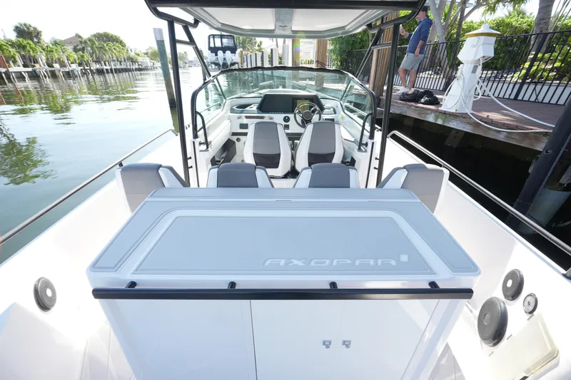Slide: The Image of 2021 Axopar 28 T-Top boat interior with seating and console, docked by a waterfront. - 30