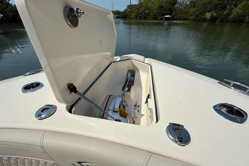 Slide: The Image of 2025 Scout 277 LXF boat anchor compartment open on calm water. - 17