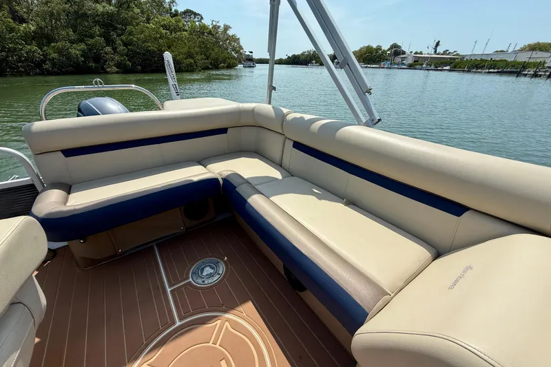 Slide: The Image of 2022 Hurricane FunDeck 2260 REF boat interior with beige and blue seating, on calm water. - 19