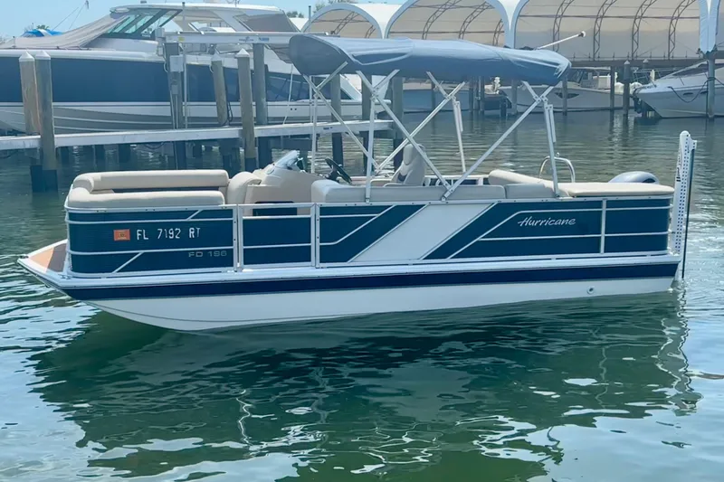 The Image of 2022 Hurricane FunDeck 2260 REF pontoon boat docked in marina, featuring blue and white design. - 2