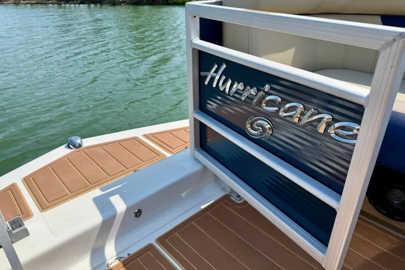 Slide: The Image of 2022 Hurricane FunDeck 2260 REF boat on water, showcasing deck and branding. - 23