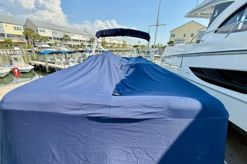 Slide: The Image of 2022 Hurricane FunDeck 2260 REF boat covered in blue tarp at marina. - 27