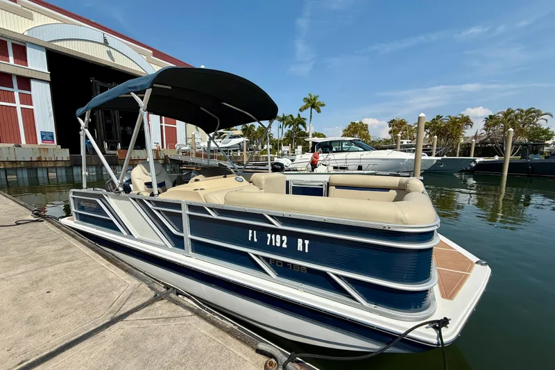 Slide: The Image of 2022 Hurricane FunDeck 2260 REF boat docked at marina under clear blue sky. - 9