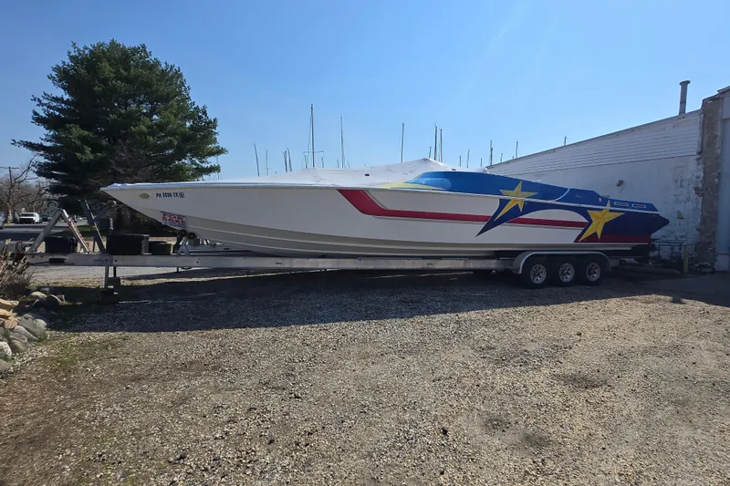 Slide: The Image of 2002 Avanti 41 speedboat with vibrant star design on trailer, parked outdoors. - 17