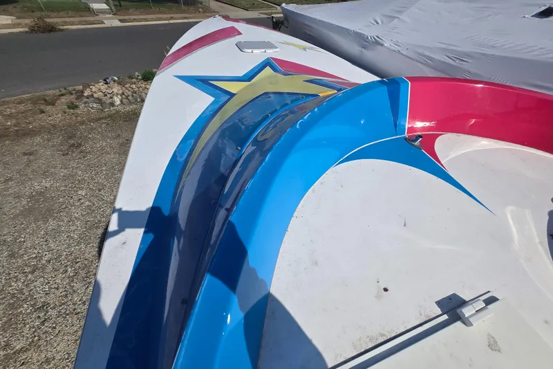 Slide: The Image of Colorful 2002 Avanti 41 boat with star design, parked outdoors on gravel. - 40