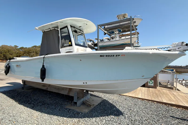 Slide: The Image of 2020 Sea Hunt Ultra 255 SE boat on a trailer at a marina. - 2