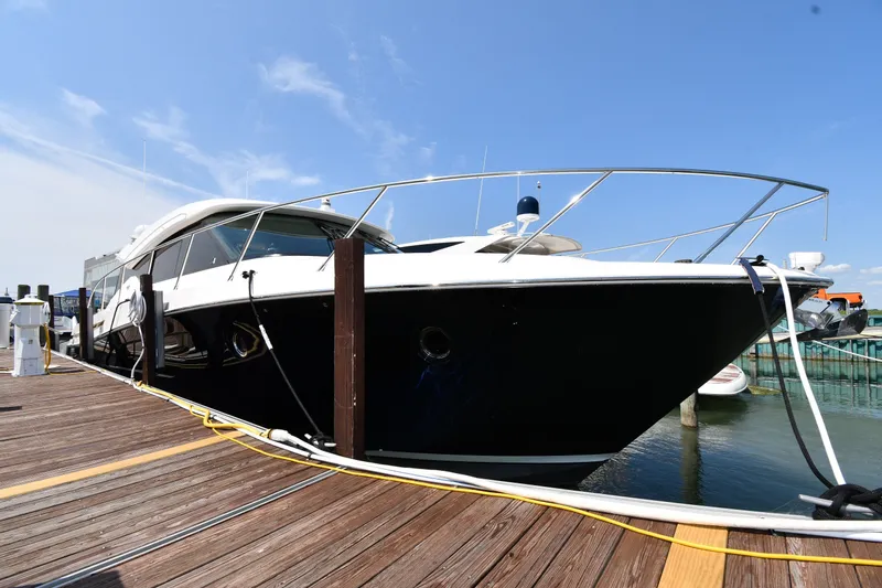 The Image of 2016 Tiara Yachts 50 Coupe docked at marina under clear blue sky. - 0