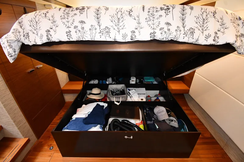 Slide: The Image of Under-bed storage in 2016 Tiara Yachts 50 Coupe, organized with clothes and accessories. - 38