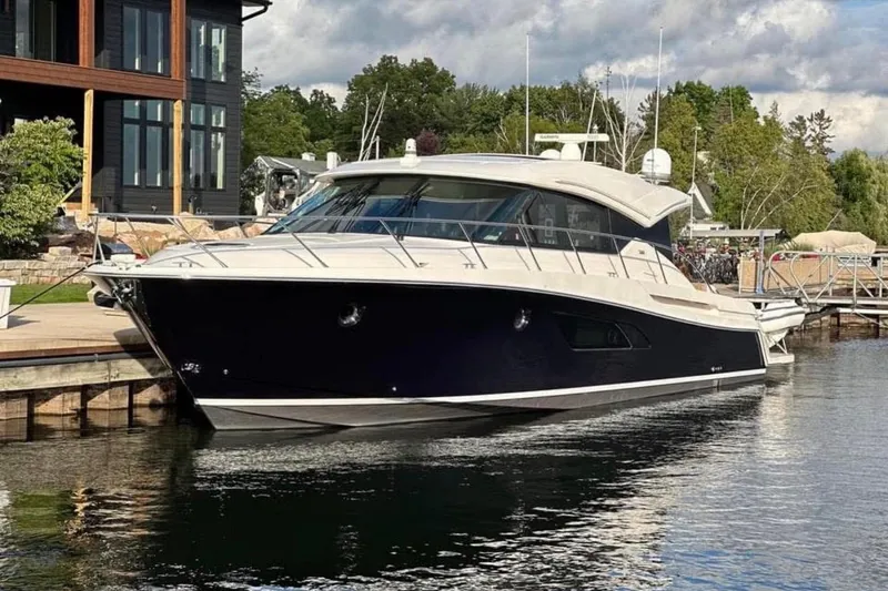Slide: The Image of 2016 Tiara Yachts 50 Coupe docked by a modern waterfront home. - 2