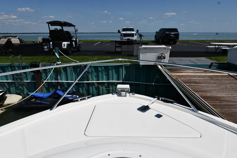 Slide: The Image of Bow view of 2016 Tiara Yachts 50 Coupe docked, with vehicles and jet ski nearby. - 5