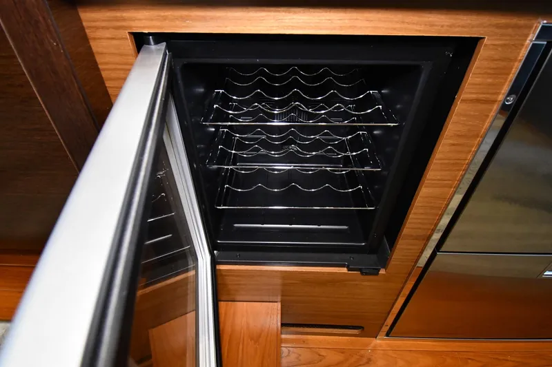 Slide: The Image of Open wine cooler in 2016 Tiara Yachts 50 Coupe, showcasing wooden cabinetry and metal racks. - 37