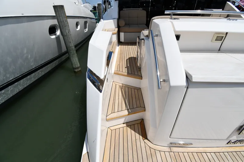 Slide: The Image of 2016 Tiara Yachts 50 Coupe, elegant teak deck, docked beside another yacht. - 16
