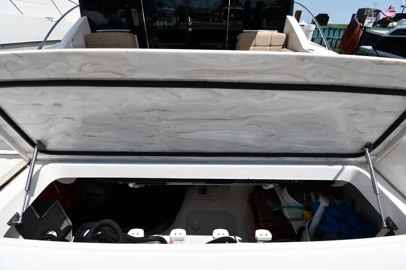 Slide: The Image of 2016 Tiara Yachts 50 Coupe storage compartment with open hatch, showcasing interior equipment. - 19