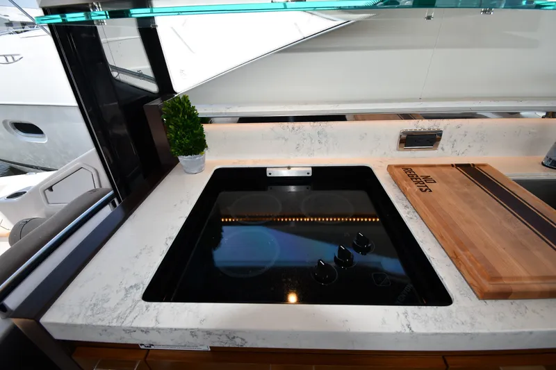 Slide: The Image of Modern kitchen area on 2016 Tiara Yachts 50 Coupe with sleek cooktop and cutting board. - 47