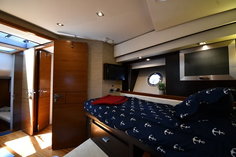 Slide: The Image of Luxurious 2016 Tiara Yachts 50 Coupe cabin interior with nautical-themed bedding and modern amenities. - 27