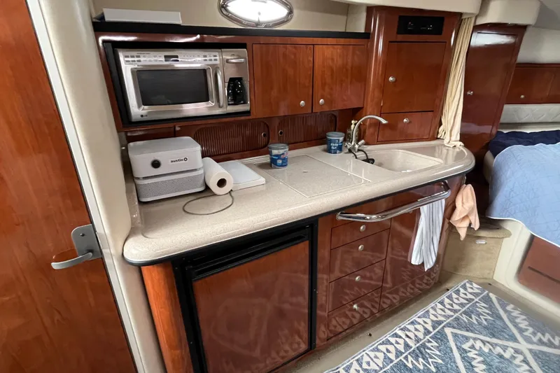 Slide: The Image of 2006 Sea Ray 340 Sundancer galley with microwave, sink, and wooden cabinetry. - 33
