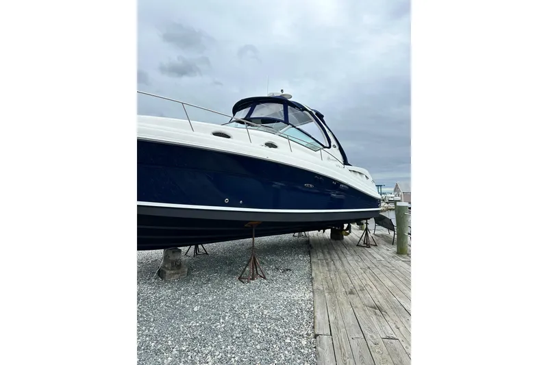 Slide: The Image of 2006 Sea Ray 340 Sundancer yacht on dry dock, blue and white exterior. - 8