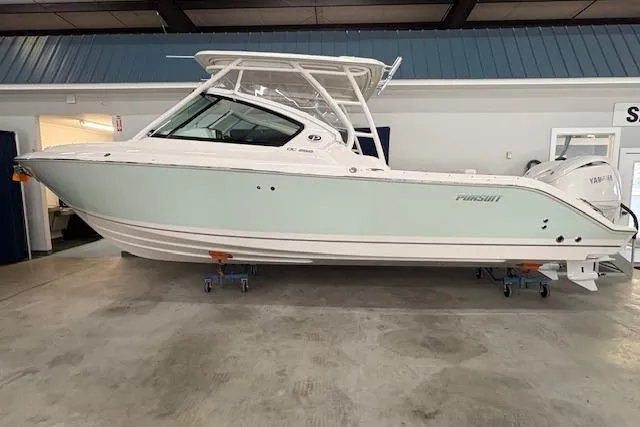 The Image of 2026 Pursuit DC 266 Dual Console boat displayed indoors on stands. - 1