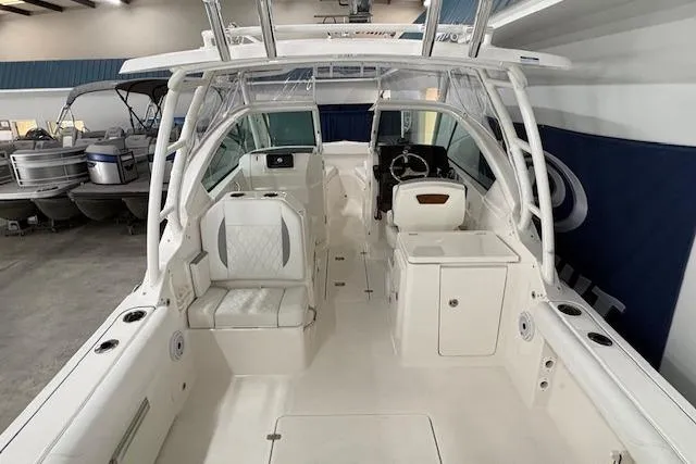 Slide: The Image of 2026 Pursuit DC 266 Dual Console boat interior with seating and helm in showroom. - 9