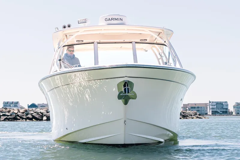 Slide: The Image of 2024 Grady-White Freedom 307 boat cruising on calm waters near coastal homes. - 6