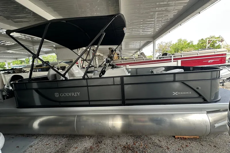 The Image of 2026 Sweetwater 2286FX pontoon boat under covered storage, featuring sleek design and canopy. - 0