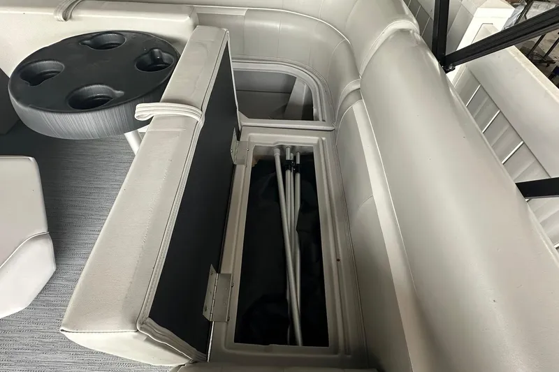 Slide: The Image of Interior of 2026 Sweetwater 2286FX boat with open storage compartment and cup holder table. - 22
