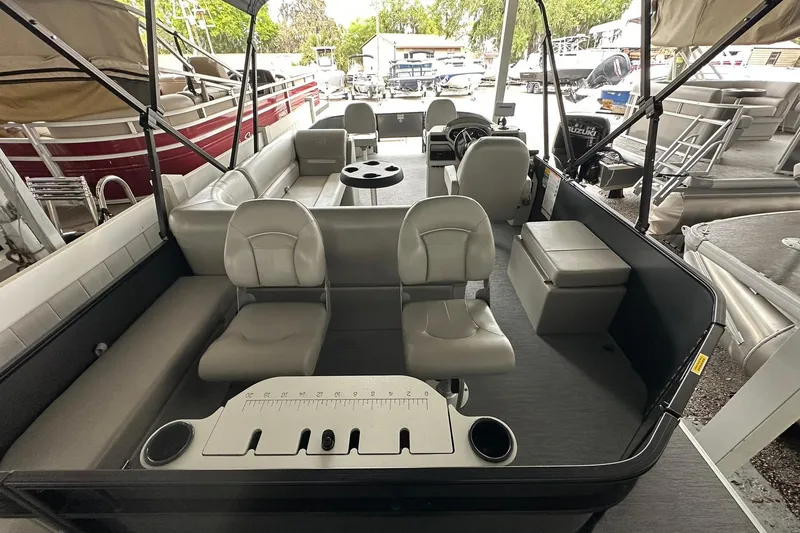 Slide: The Image of 2026 Sweetwater 2286FX pontoon boat interior with seating and helm, displayed in a marina. - 25