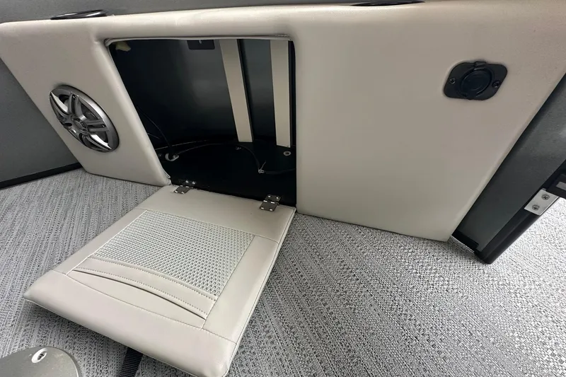 Slide: The Image of Sweetwater 2286FX 2026 boat interior storage compartment with speaker and cushioned panel. - 8