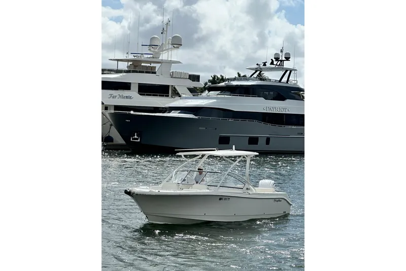 The Image of 2023 Edgewater 248CX Crossover boat cruising near luxury yachts on a sunny day. - 0