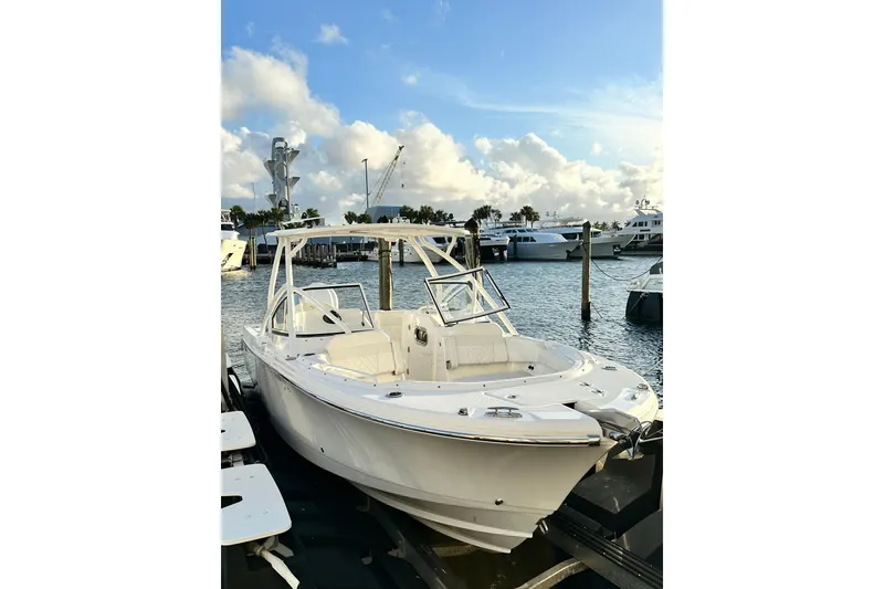 Slide: The Image of 2023 Edgewater 248CX Crossover boat docked at a marina under a blue sky. - 10