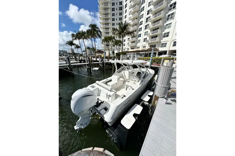 Slide: The Image of 2023 Edgewater 248CX Crossover boat docked near waterfront apartments. - 2